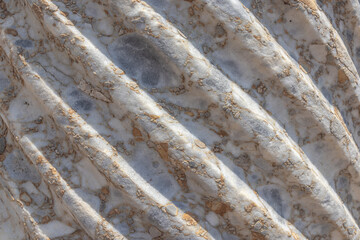 Spiral sculptural relief on the surface of a column in the ancient city of Perge in Turkey. Antique columns subject to erosion and ruins of an ancient city. Background of the column surface.