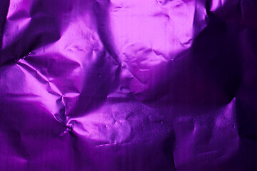 Crumpled purple foil creating unique textures and patterns under soft light in a compact space