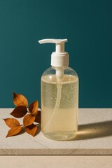 A transparent liquid bottle with pump dispenser.  The bottle is filled with clear liquid and is sitting on a stone surface