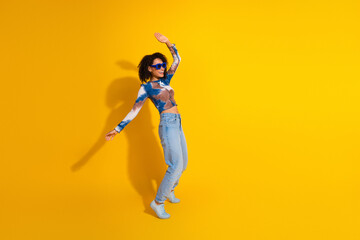 Young fashionable woman in casual attire posing against vibrant yellow background, showcasing...