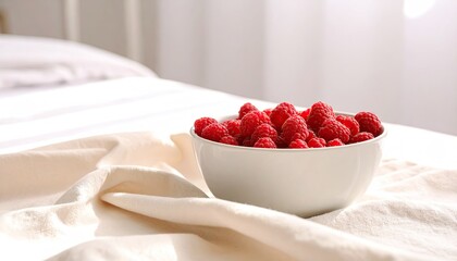 Fresh raspberries in a bowl on a bed