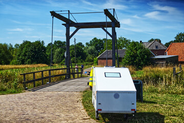 White caravan parking on brick road beside raised drawbridge, highlighting scenic dutch countryside...