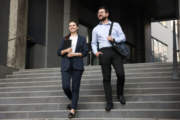 Happy coworkers on stairs near office building