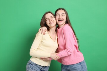 Happy friends hugging each other on green background