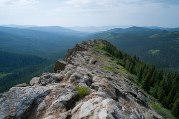 Rocky ridge trail with expansive forest view under cloudy sky
