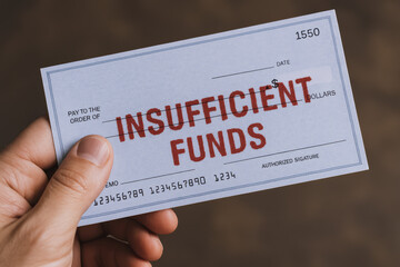 A holds a bounced check stamped with a notice indicating insufficient funds symbolizing financial setbacks and payment challenges in business transactions