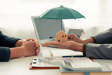 Insurance agent covers the house with a green umbrella, insurance concept, prepare for the...
