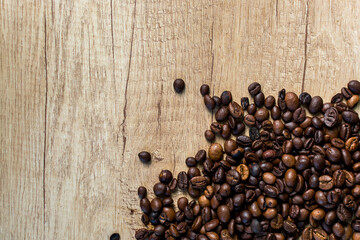 A pile of roasted coffee beans spread on a natural rustic wooden surface. Ideal for food, cafe, or coffee-themed designs.