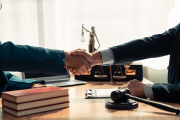 Close-up of lawyer and client shaking hands on table, symbolizing trust in legal contract with a...