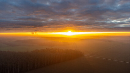 Aerial view captures a vibrant sunrise over a misty landscape