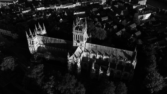 Aerial black and white view of Selby Abbey showcases its Gothic architecture amidst surrounding buildings and trees.