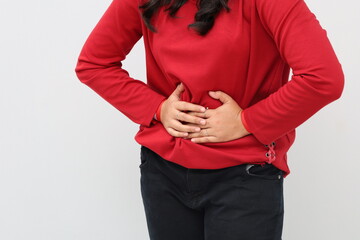 Close up photo of woman standing holding stomach, stomach ache concept, standing isolated on white background.