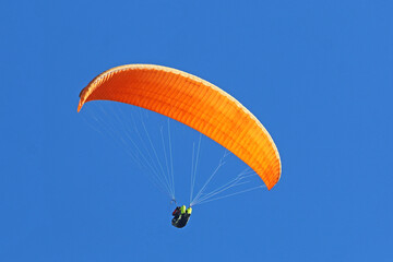 Paraglider flying in a blue sky	