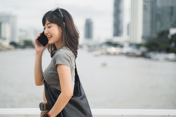 Happy solo Southeast Asian woman teenager blogger express joy with smartphone. World travel...