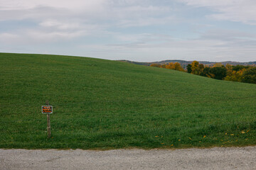 Beautiful green hillside with warning sign in rural area during early evening hours