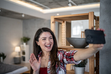 Happy woman making a video call and waving at home