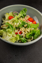 Pasta salad green leaf lettuce, tomato, pasta, onion fresh delicious gourmet food background on the table rustic food top view copy space keto and paleo diet vegan and vegetarian food