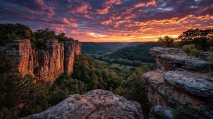 A breathtaking sunset view over rugged cliffs and lush valleys, showcasing dramatic clouds and vibrant colors in the sky.