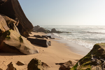 Rocky beach with sandstone boulders and ocean waves at sunrise