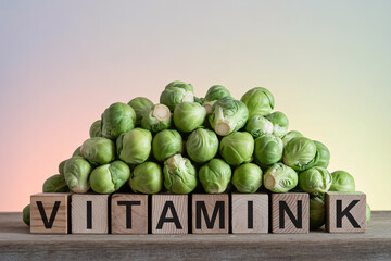 Brussels sprouts stacked on wood with blocks spelling “Vitamin K”. Rustic studio scene highlighting nutrient-rich greens