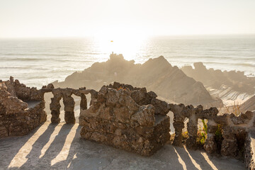 Sunset view over rugged coastline with stone wall foreground