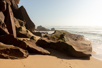 Rocky beach with sandstone boulders and ocean waves at sunrise
