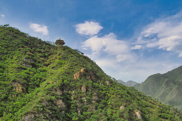 A small tower along Great Wall of China in Beijing surrounding by a lush green trees in the mountain.