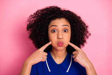 Portrait of a fashionable young woman making a playful gesture against a vibrant pink background