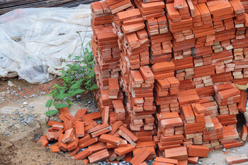 High pile of orange bricks prepared for bricklaying wall construction jobs