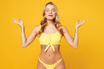 Young spiritual woman wear bikini swimsuit rest near hotel pool hold hands in yoga om aum gesture...