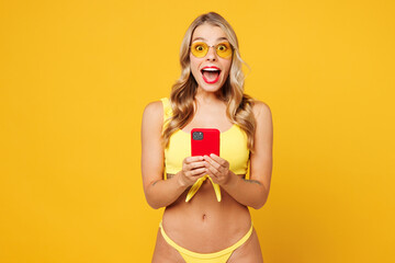 Young shocked surprised fun beautiful sexy woman wear bikini swimsuit rest near hotel pool hold in...