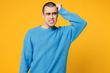 Young sad embarrassed mistaken middle eastern man he wearing blue sweatshirt casual clothes looking aside on area mock up isolated on plain yellow orange background studio portrait. Lifestyle concept.