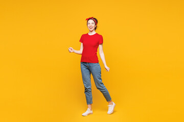 Full body young smiling happy cool woman she wearing red t-shirt casual clothes walking going looking camera with toothy smile isolated on plain yellow background studio portrait. Lifestyle concept.