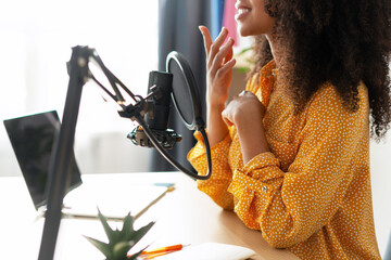 Young woman recording podcast in home studio using professional microphone and laptop