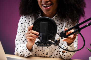 Smiling woman adjusting microphone and preparing for recording podcast selective focus