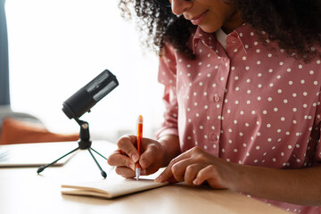 African American woman, content creator taking notes while recording podcast episode