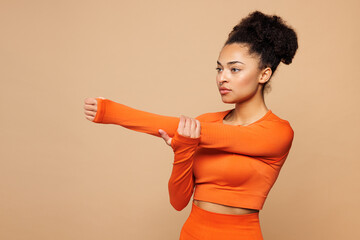 Sideways young strong fitness trainer instructor sporty woman sportswoman wear orange clothes spend...