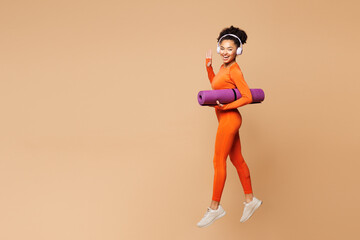 Full body side view young fitness trainer instructor woman she wear orange clothes headphones spend...