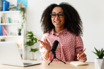 Young smiling African American woman recording podcast from her home studio