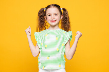Little fun cute kid child girl 8-9 years old wears green t-shirt doing winner gesture celebrate...