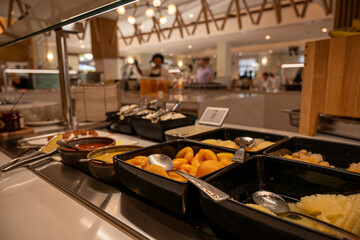 A buffet with a variety of food, including fruit and vegetables. Scene is casual and inviting, as the food is displayed in a way that makes it easy for people to grab what they want