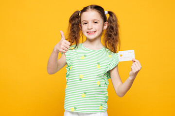 Little smiling fun cute kid child girl 8-9 years old wears green t-shirt hold mock up of credit...