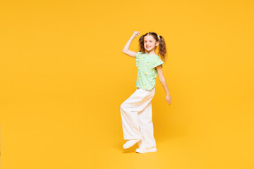 Full body little cute kid child girl 8-9 years old wears green t-shirt doing winner gesture...