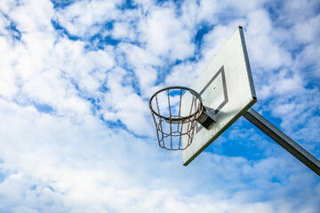 Sunny day at the outdoor court with a basketball hoop against a blue sky
