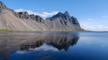Crystalline waters showcase perfect reflections of towering mountains in Icelands breathtaking nature. Stokksnes beach Vestrahorn Iceland