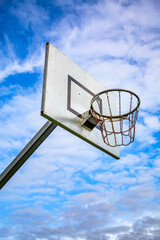 Sunny day at the outdoor court with a basketball hoop against a blue sky