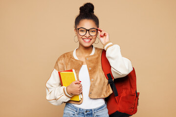 Young smiling happy smart girl student wears casual clothes backpack bag touch glasses hold books look camera isolated on plain pastel light beige background. High school university college concept.