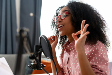 Young African American woman recording podcast from her home studio making an ok sign