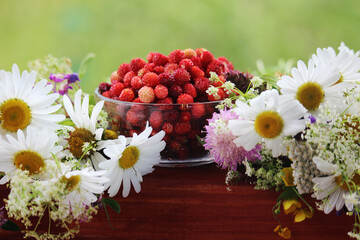 A glass bowl with strawberry and a daisy bouquet