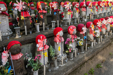 Serene Jizo statues, guardians of children who died before their parents, adorned with red hats and...